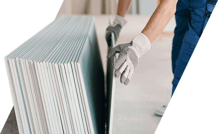 person grabbing a sheet of drywall